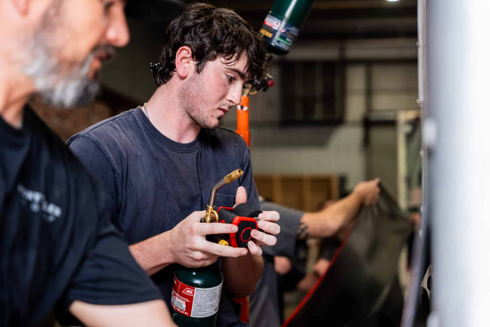 Employee Applying Vehicle Wrap In Workshop